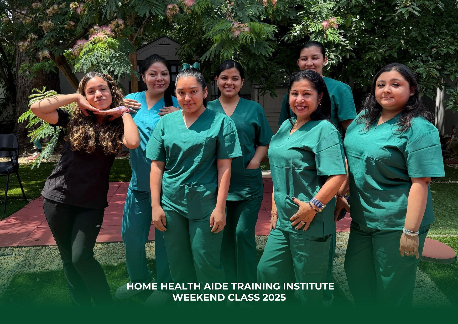 A group of people wearing green scrubs pose for a class photo outdoors on a lawn, with text at the bottom.