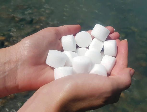 A person is holding a pile of white pills in their hands
