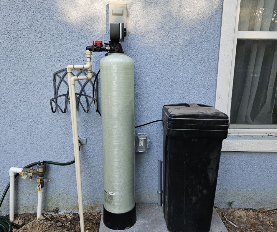 A water filter is sitting on a wooden floor next to a tank.