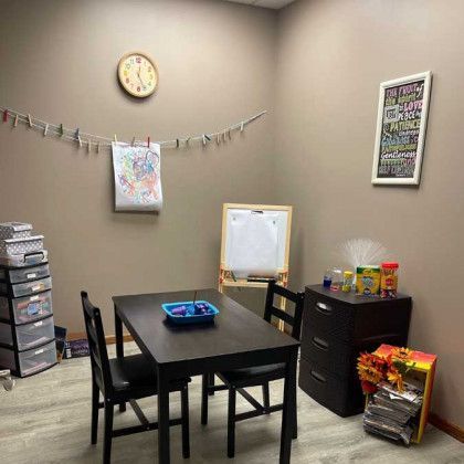 A child's play area with a table, chairs, art supplies, and storage bins.
