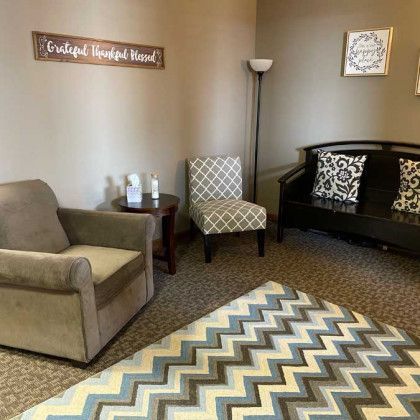 Cozy waiting room with armchair, chair, bench, rug, and inspirational wall art.