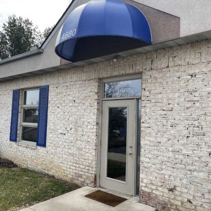 Building entrance with blue awning and shutters; address 4680 above the door.