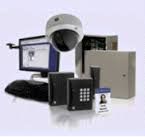 Security camera, keypad access panel, and monitor on a desk with a badge holder.