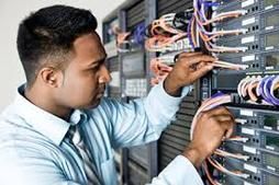 Technician connecting network cables in a server rack data center