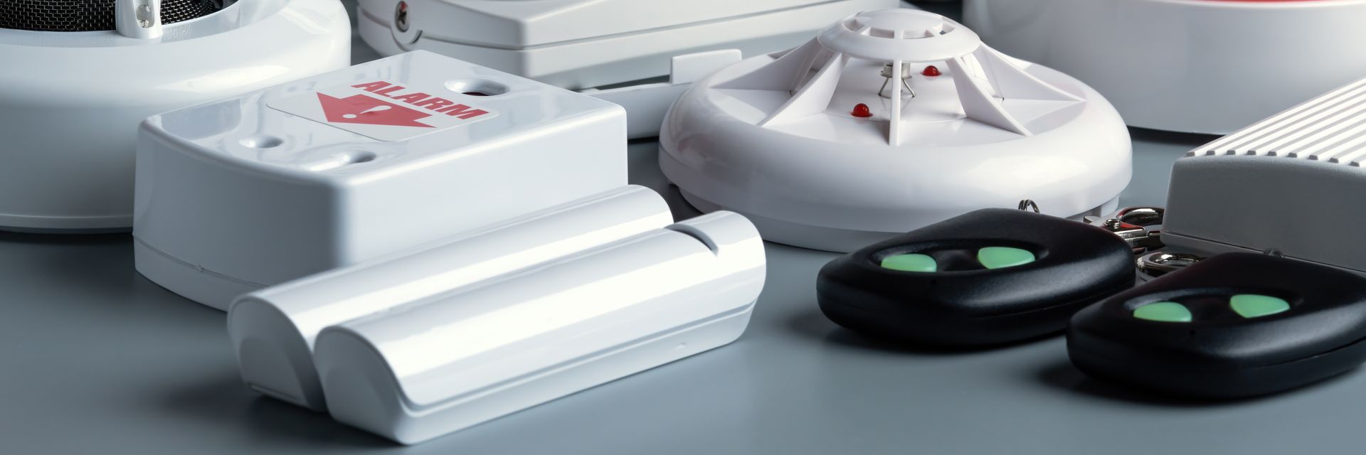 White electronic devices and black round remotes arranged on a gray surface