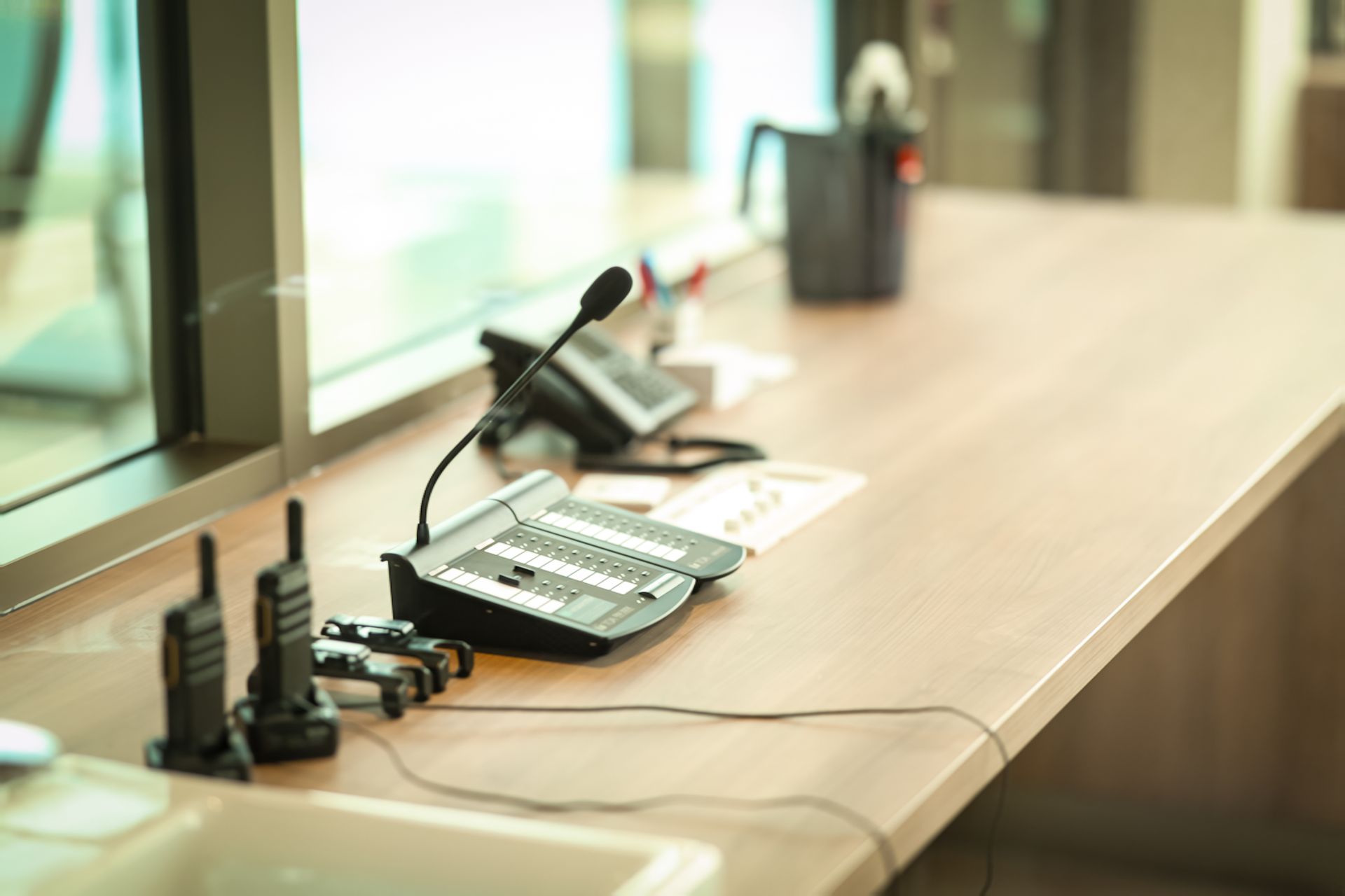 Conference room table with microphone, phone, and paperwork near a window