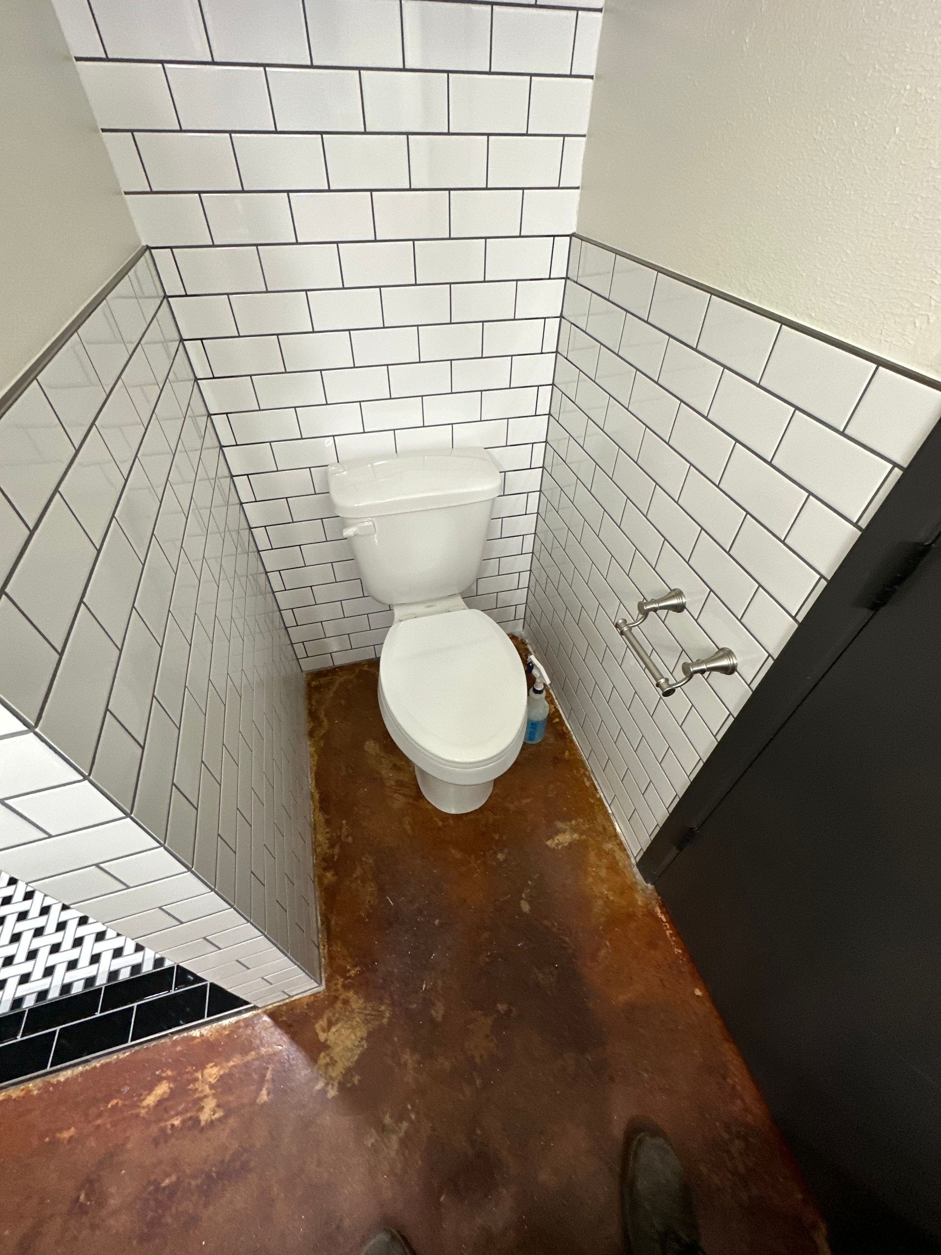Small tiled restroom with a toilet and brown floor, viewed from the doorway.