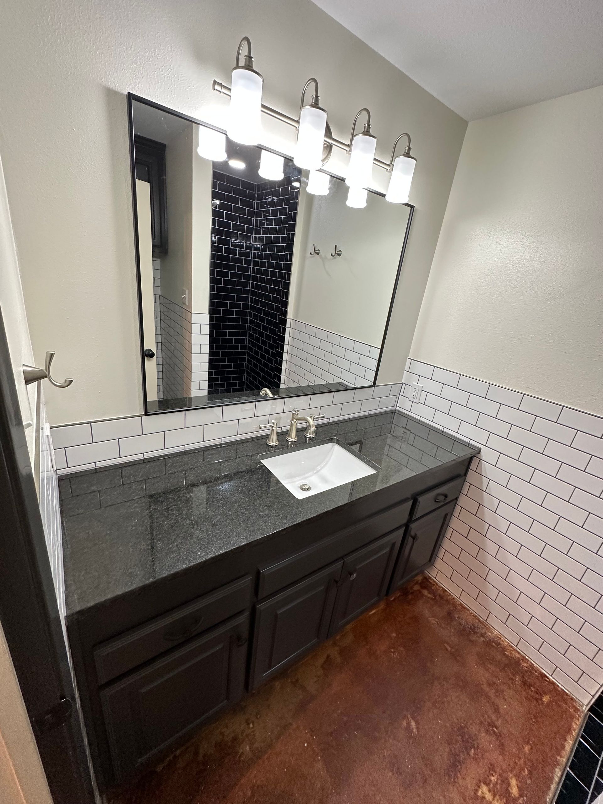 Bathroom vanity with dark cabinets, large mirror, and lit light fixtures above a sink.
