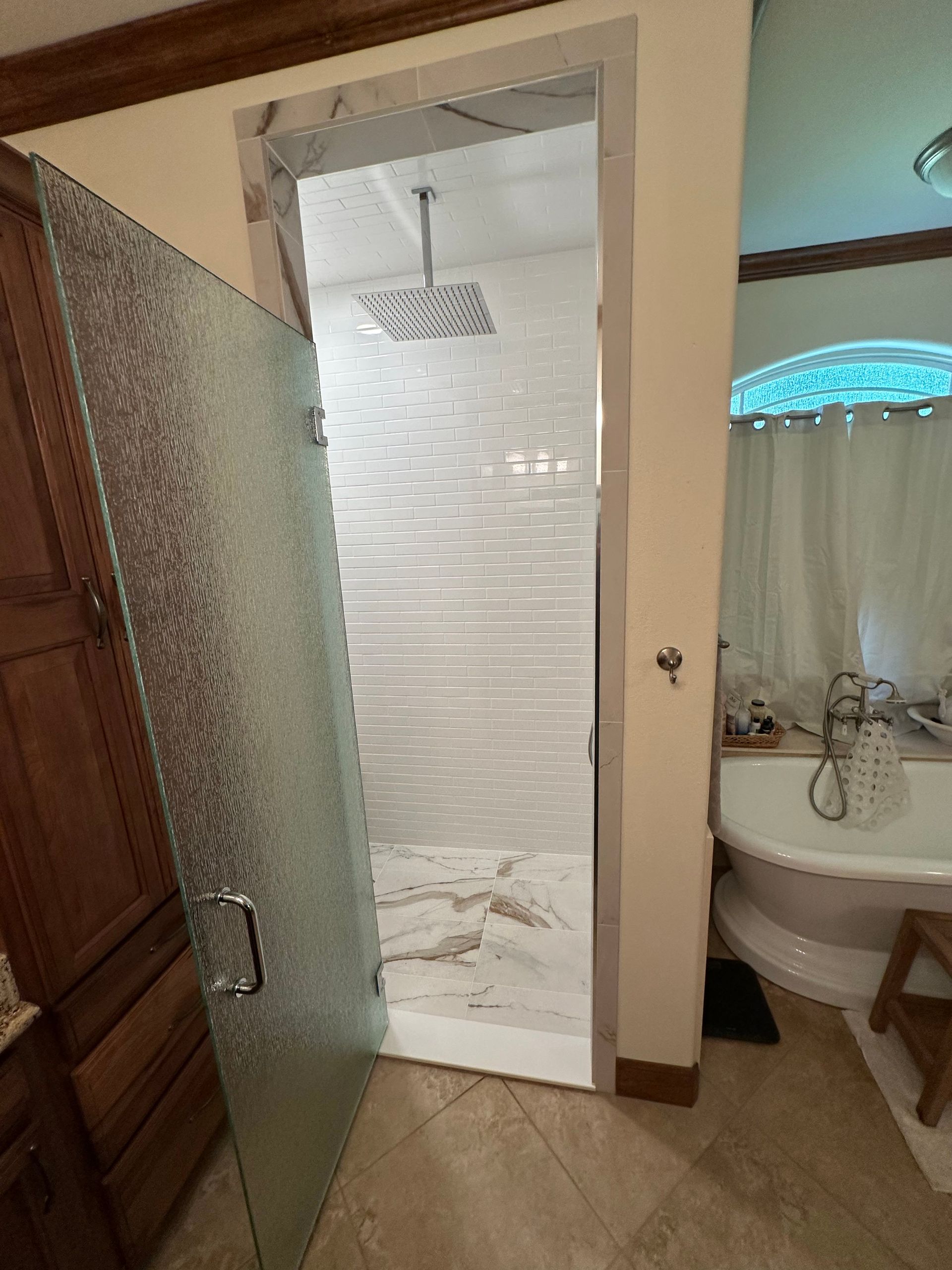 Bathroom with open shower door, glass walls, white tile, and vanity sink with blue accent lighting.