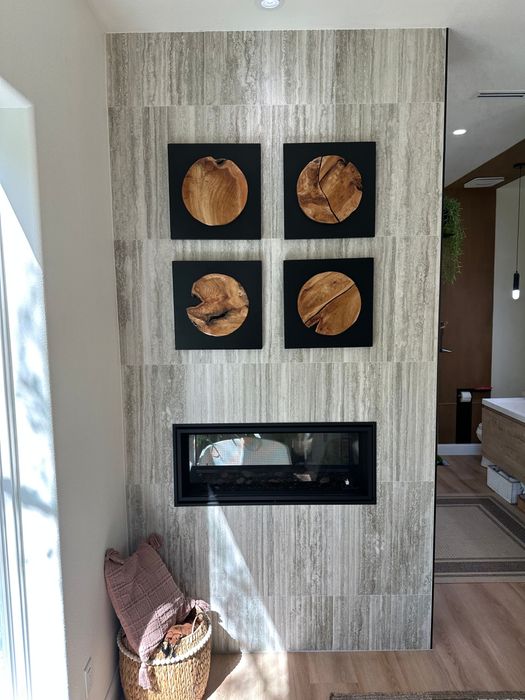 Wall-mounted fireplace with four circular art pieces above it and a basket beside a textured accent wall.