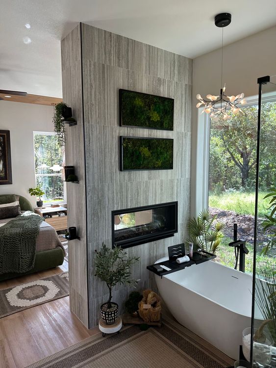 Modern living room with a concrete fireplace, hanging chair, and large window overlooking greenery