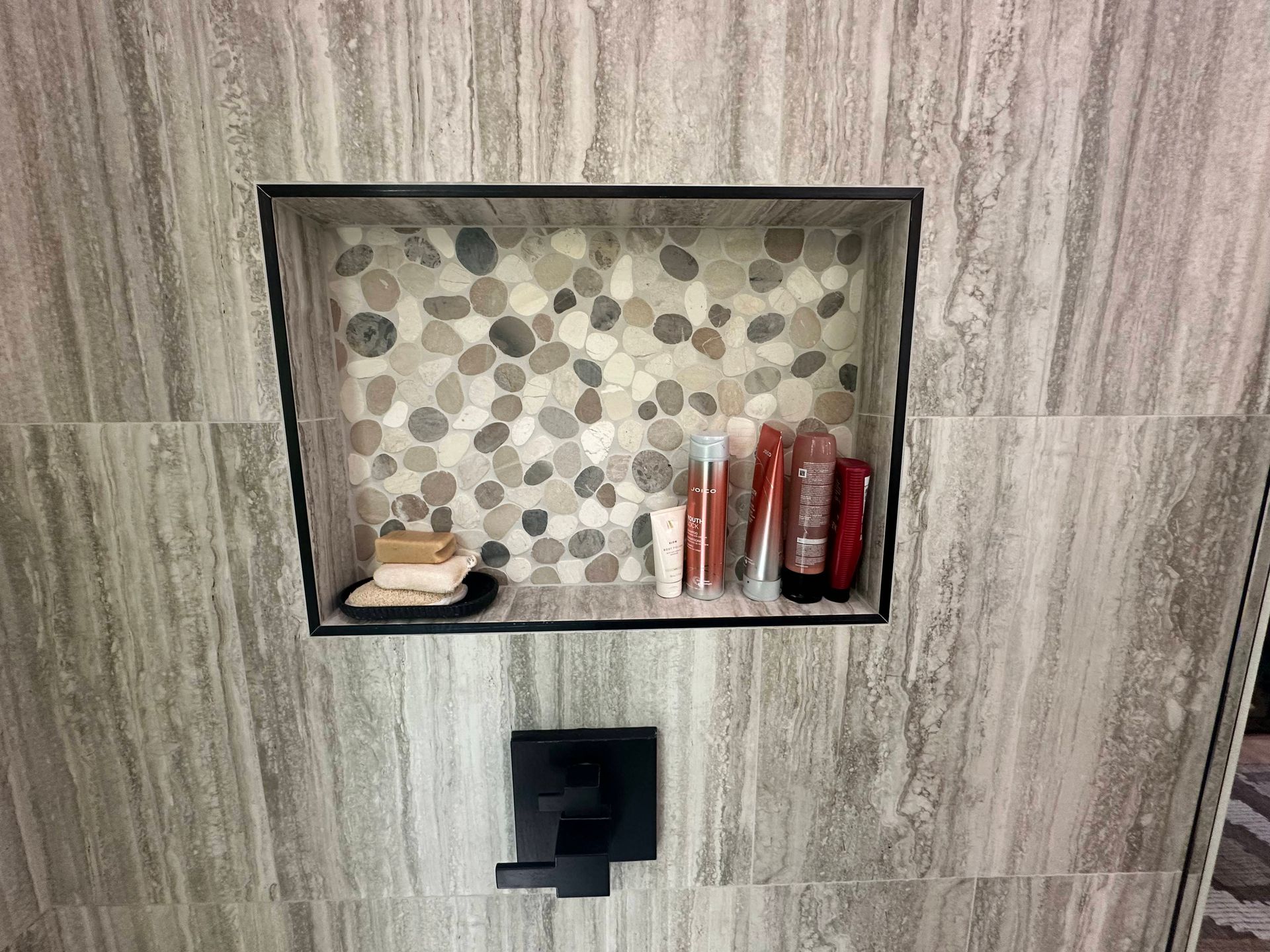 Built-in bathroom shelf with toiletries above a wall-mounted toilet paper holder