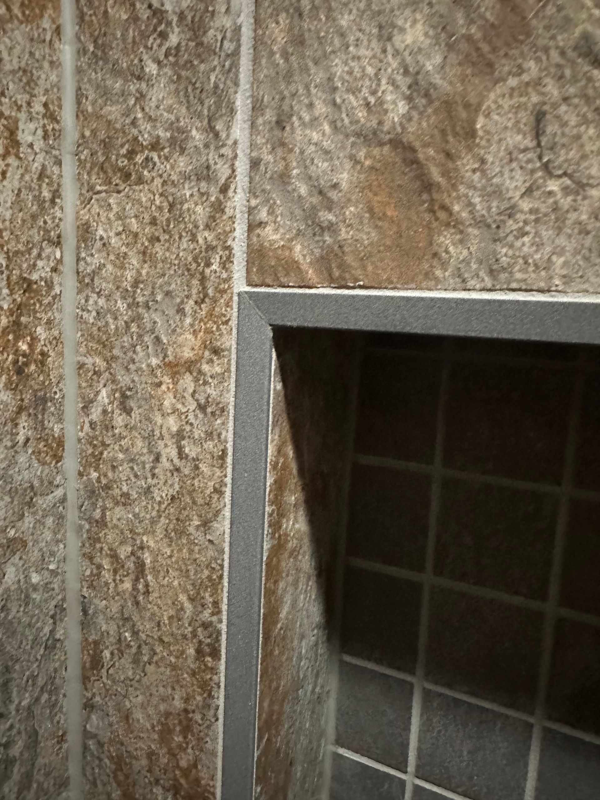 Close-up of a stone-tiled fireplace surround with a dark tiled interior opening