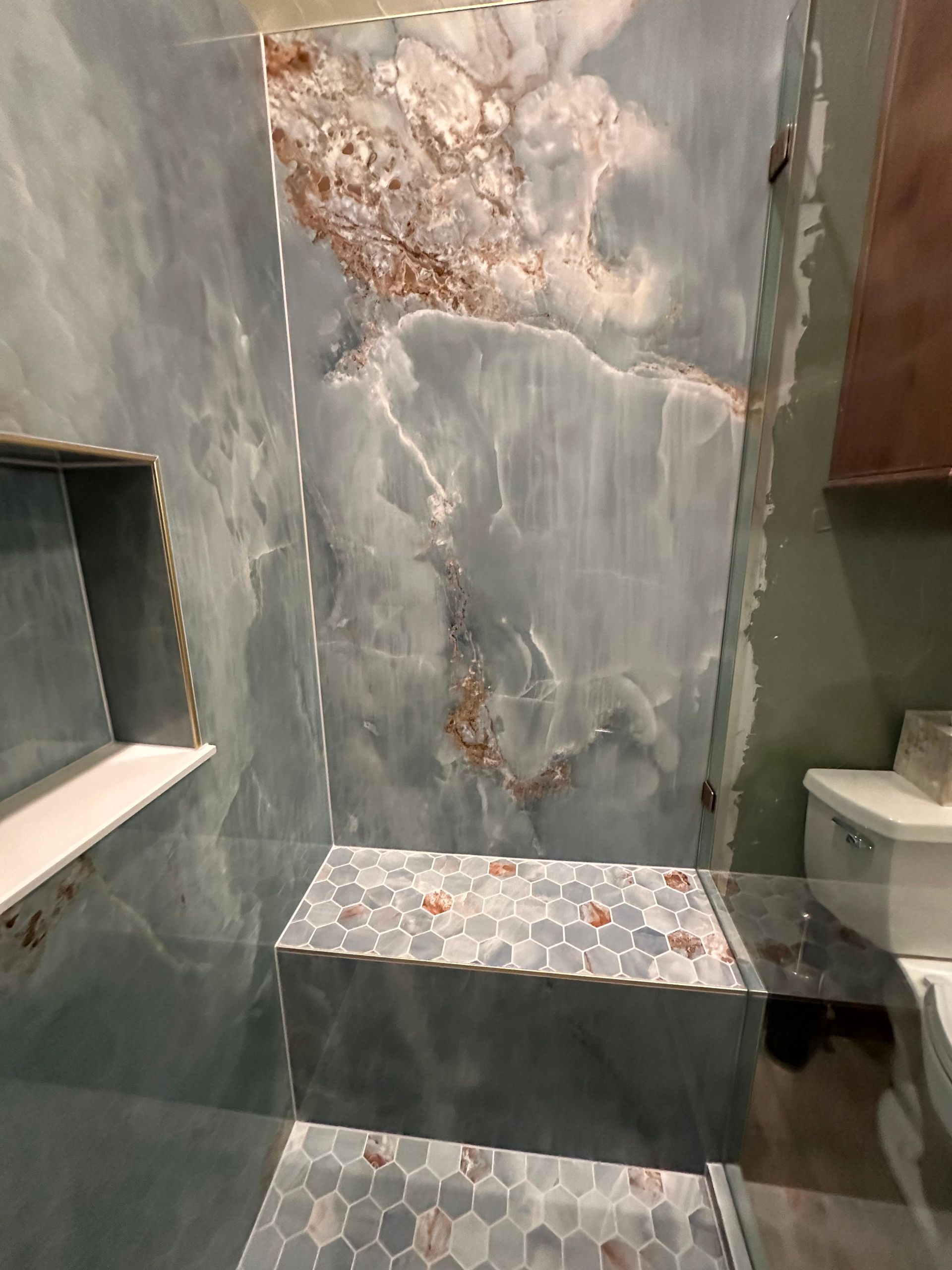 Marble-tiled shower with a built-in bench and recessed shelf in a bathroom