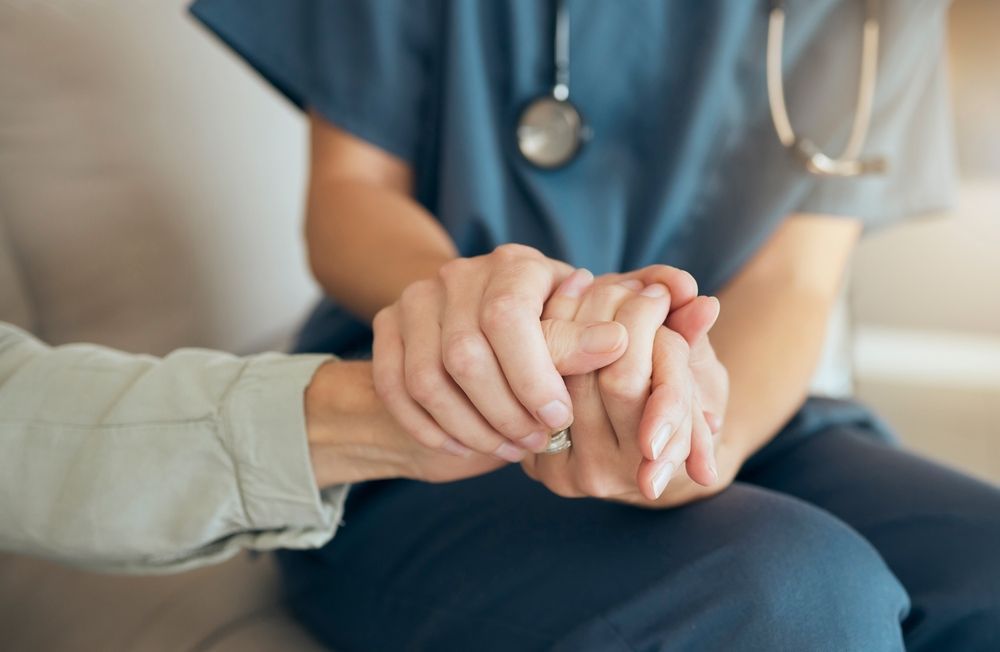 Medical professional holding the hands of a patient for support.