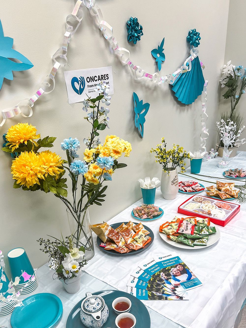 Buffet table decorated with flowers, snacks, and party decorations in shades of blue and yellow.