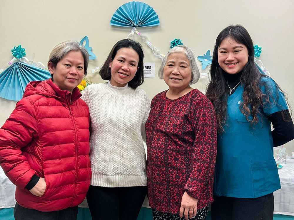 Four people pose together, smiling, in front of a decorated wall.