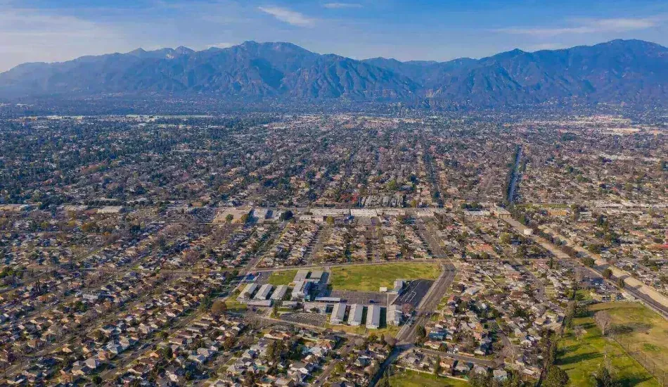 An aerial view of Arcadia CA set against a backdrop of a large mountain range under a blue sky.