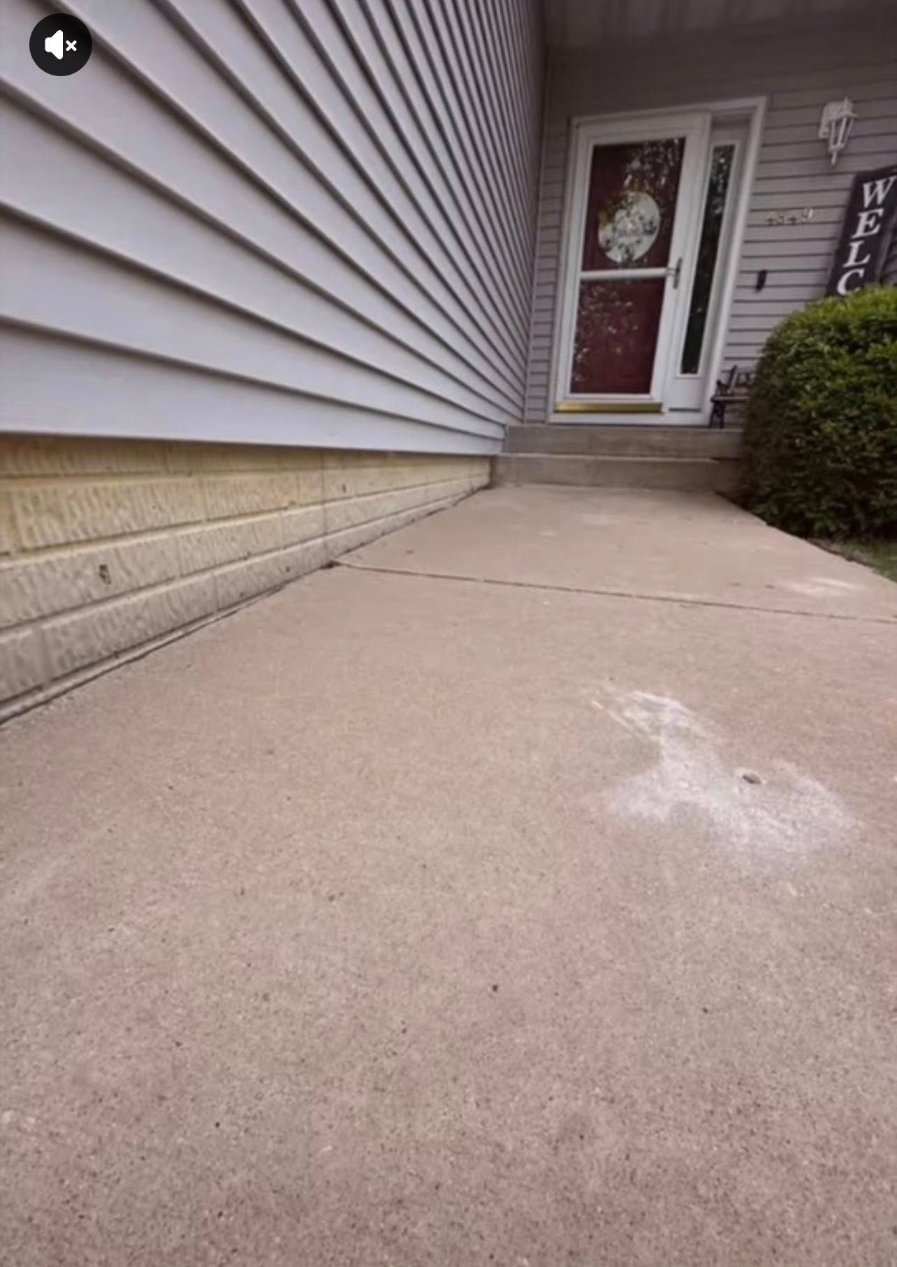 Concrete walkway leading to a front door with siding on one side. White residue is on the concrete.