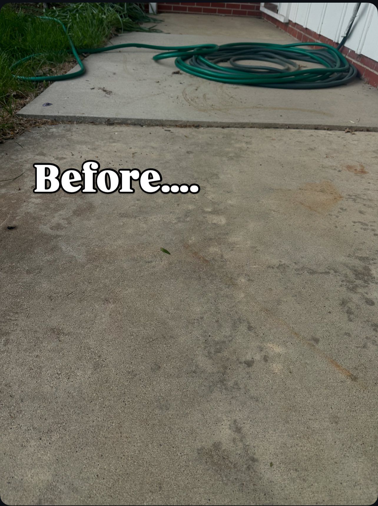 Concrete patio before cleaning, with a green hose coiled and grass visible.