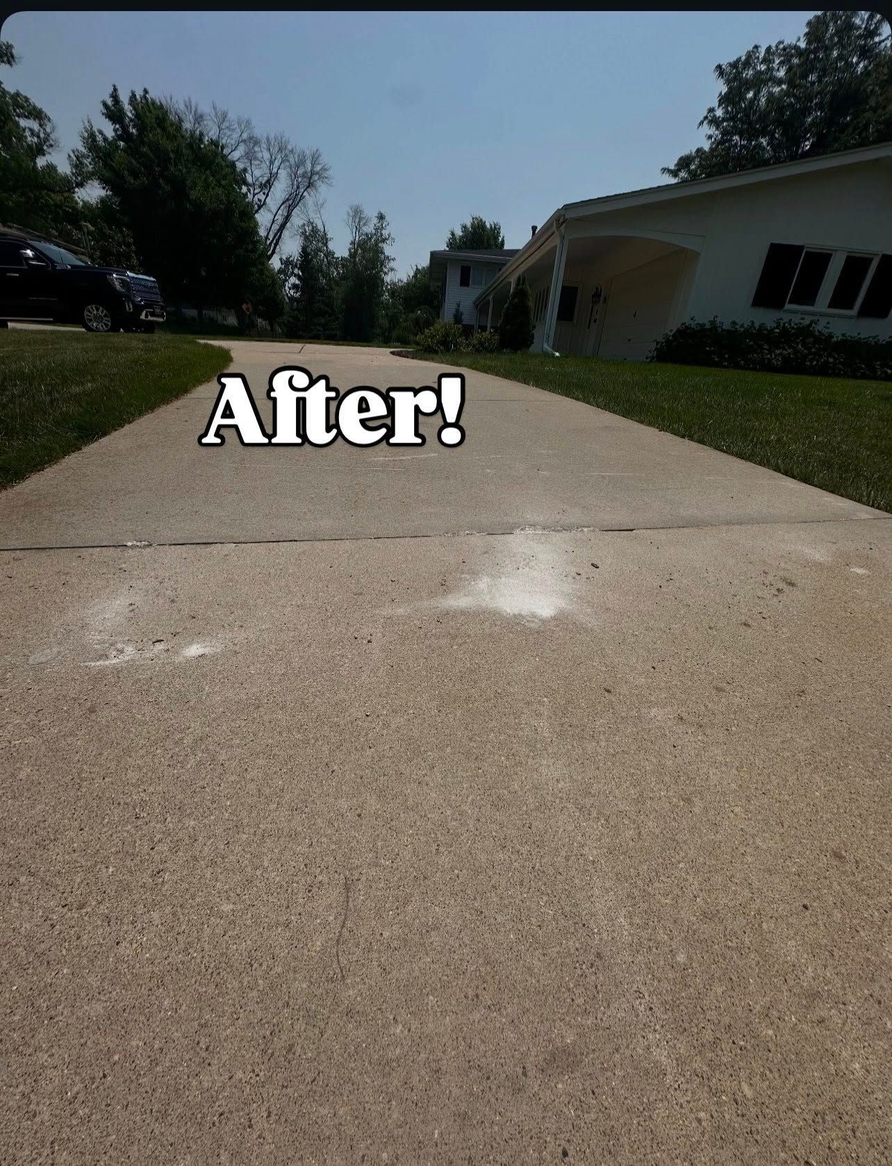 Concrete driveway in sunlight, leading to a house. Text 