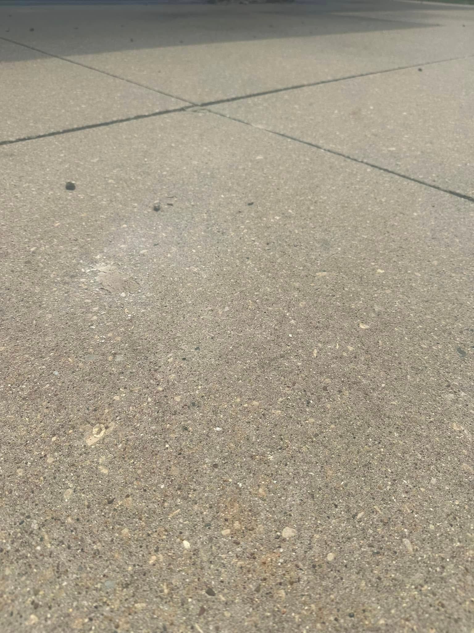 Close-up of a textured, grey concrete surface with expansion joints and scattered small debris.