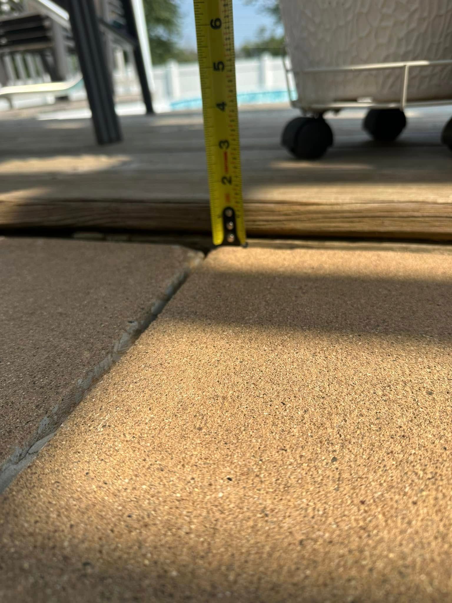A tape measure showing a gap between a deck and patio stones. The gap measures about 3/8 of an inch.