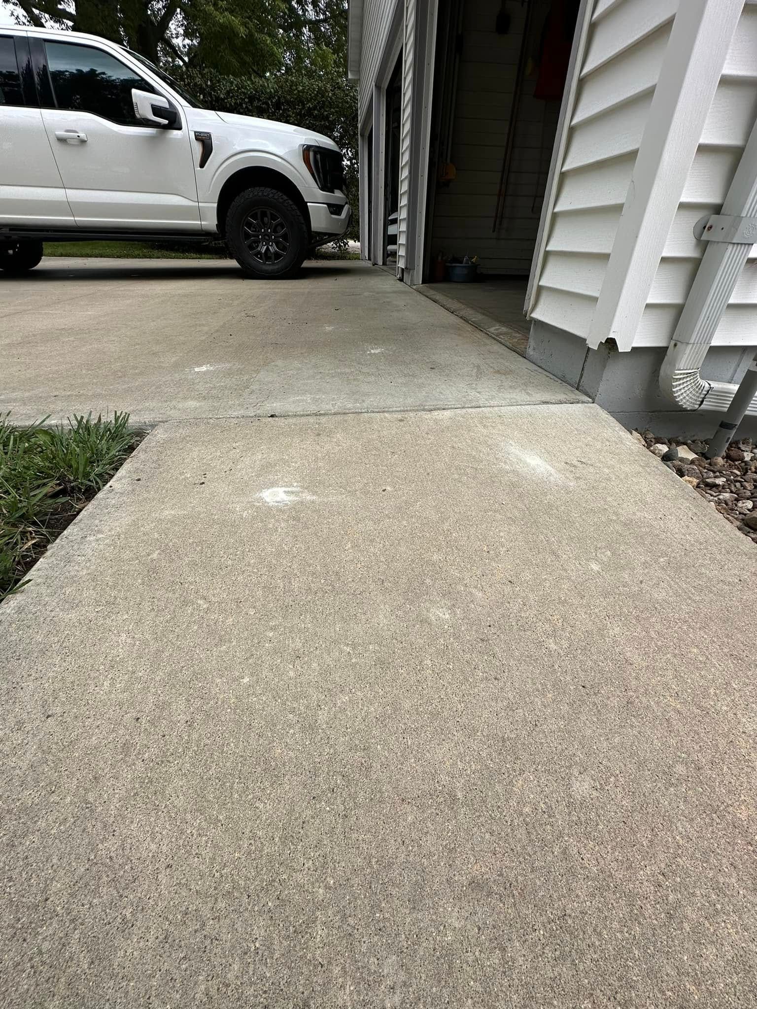 Concrete walkway leads to a garage with a white truck parked in front.