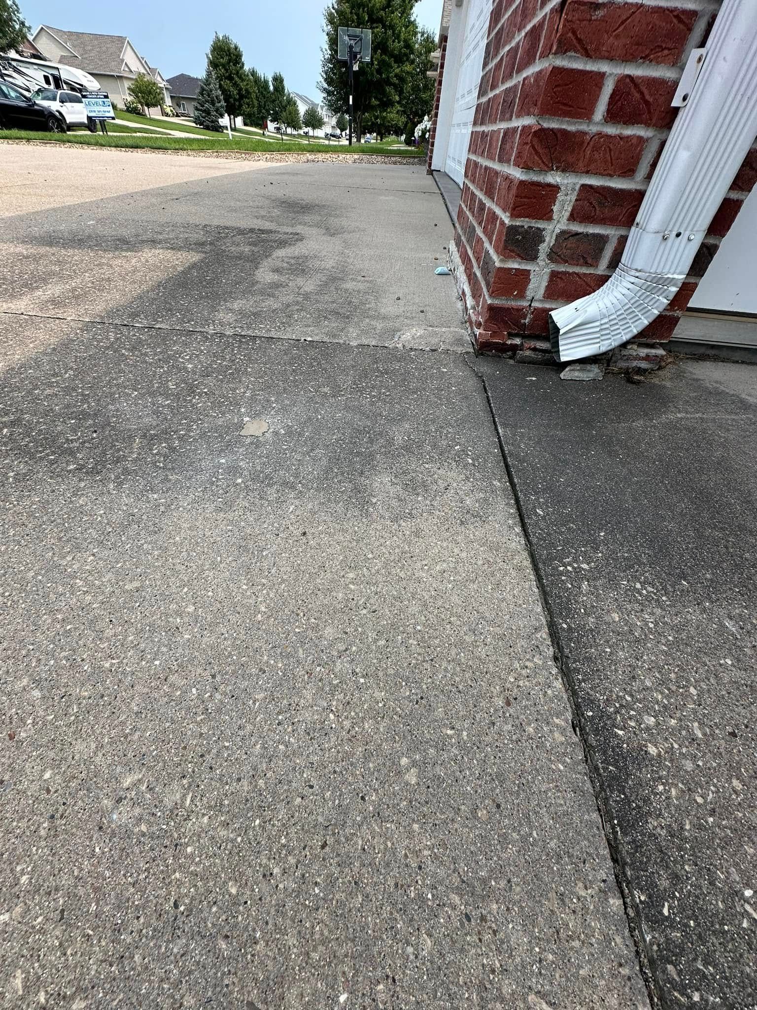 Concrete driveway next to a brick wall and a white gutter.