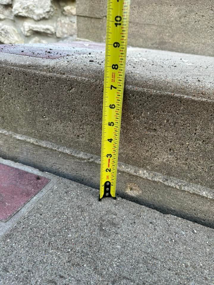 Yellow tape measure next to a concrete step, measuring just over 2 inches in height.