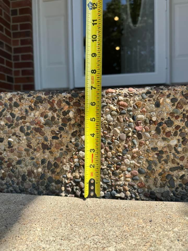 Tape measure against a concrete step with pebble aggregate, measuring about 9 inches high.