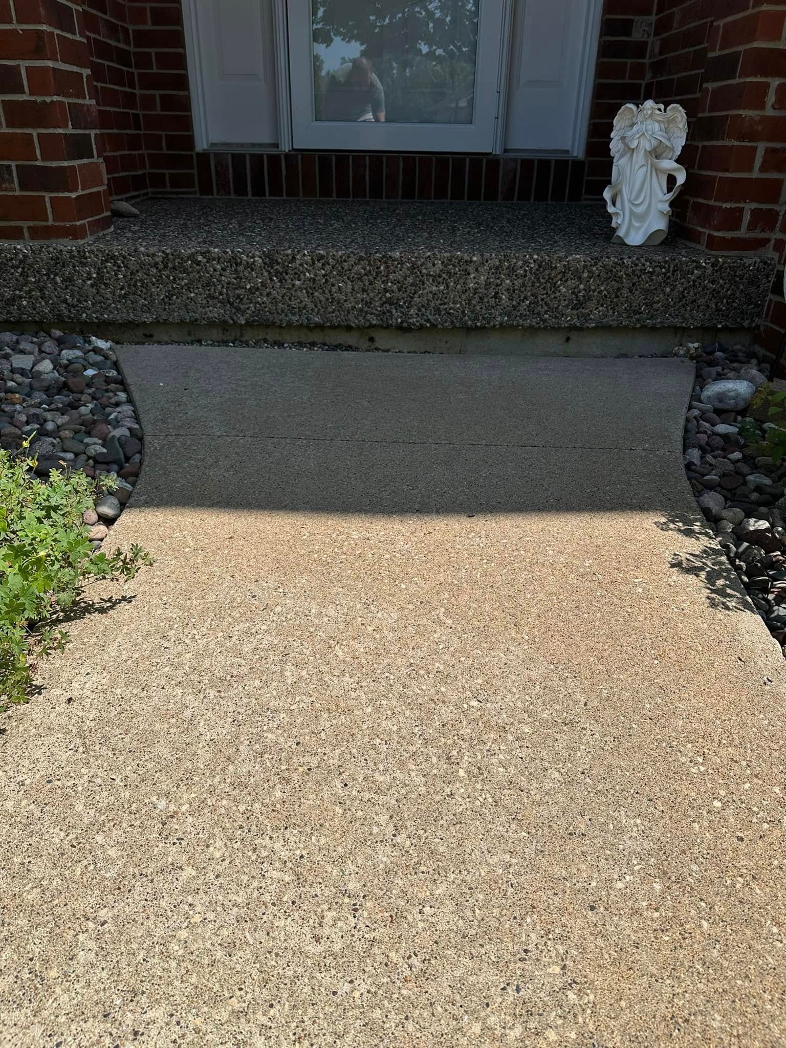 Pathway and entryway with stone steps leading to a white door. A small angel statue sits to the right.