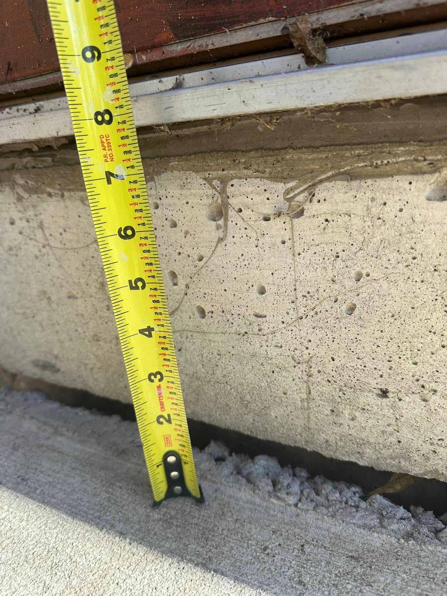Yellow tape measure next to concrete foundation, measuring approximately 7 inches.