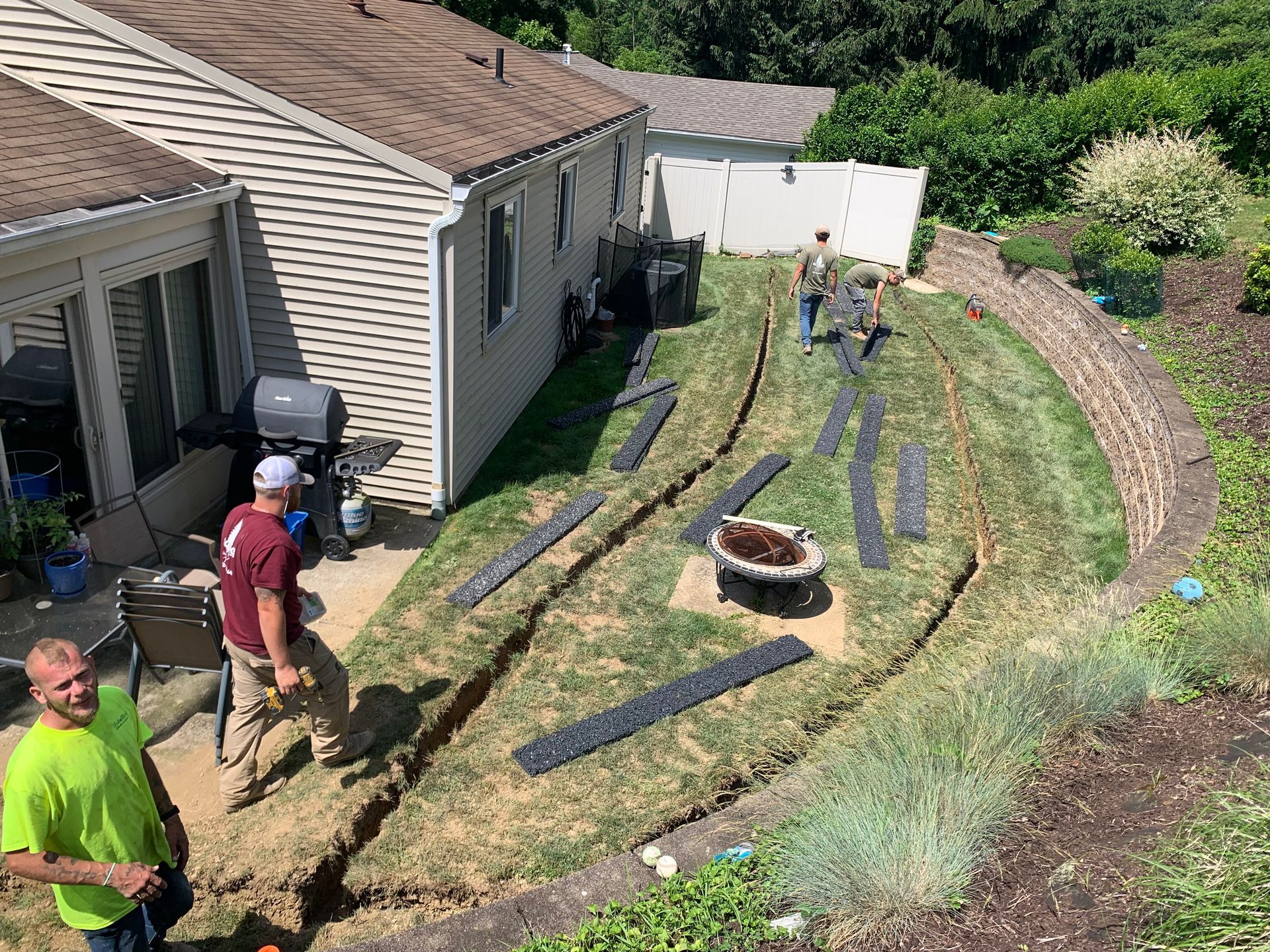 A group of men are working on a lawn in front of a house.