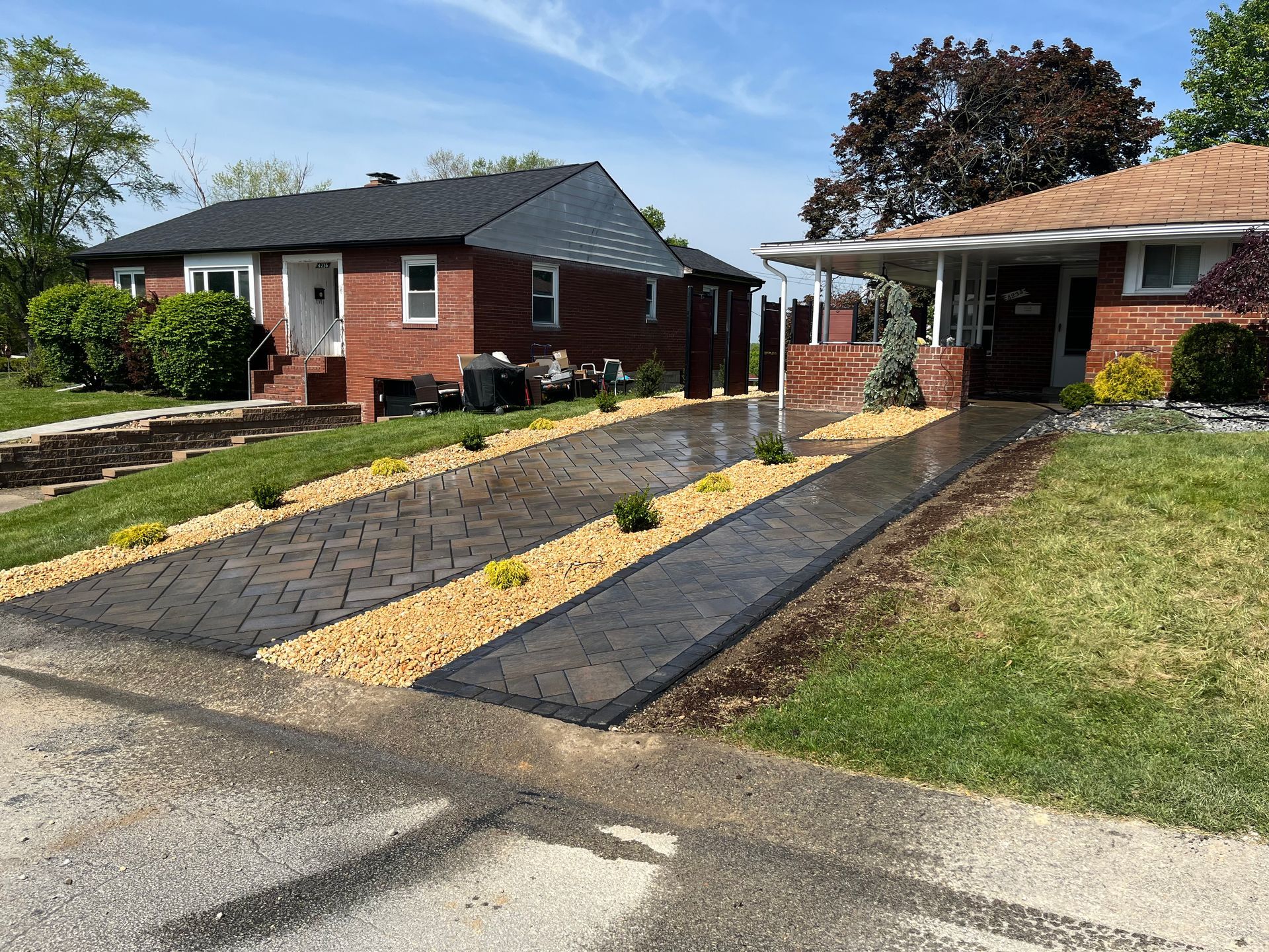 A brick house with a concrete driveway in front of it.