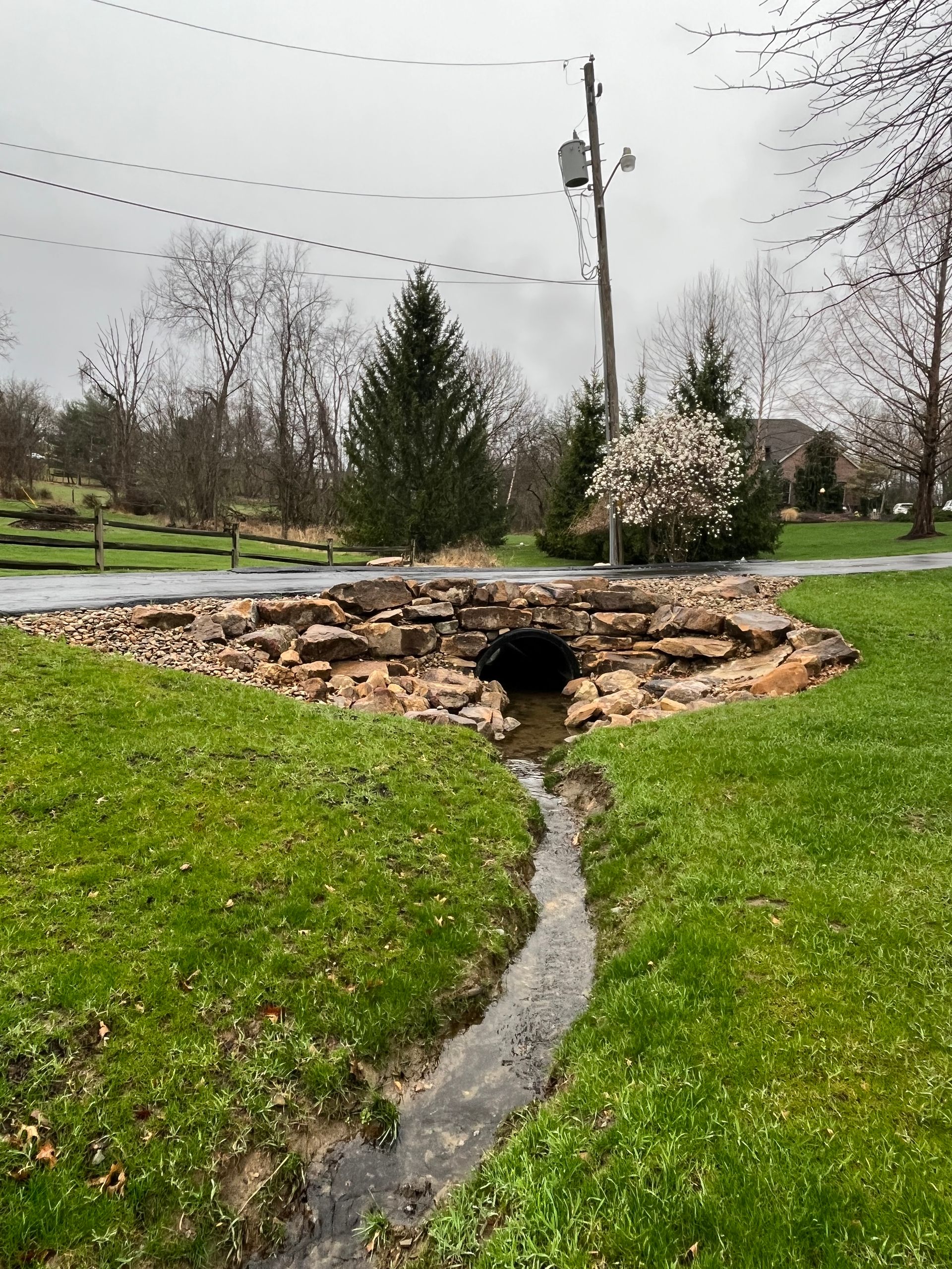 A stream running through a grassy area next to a road