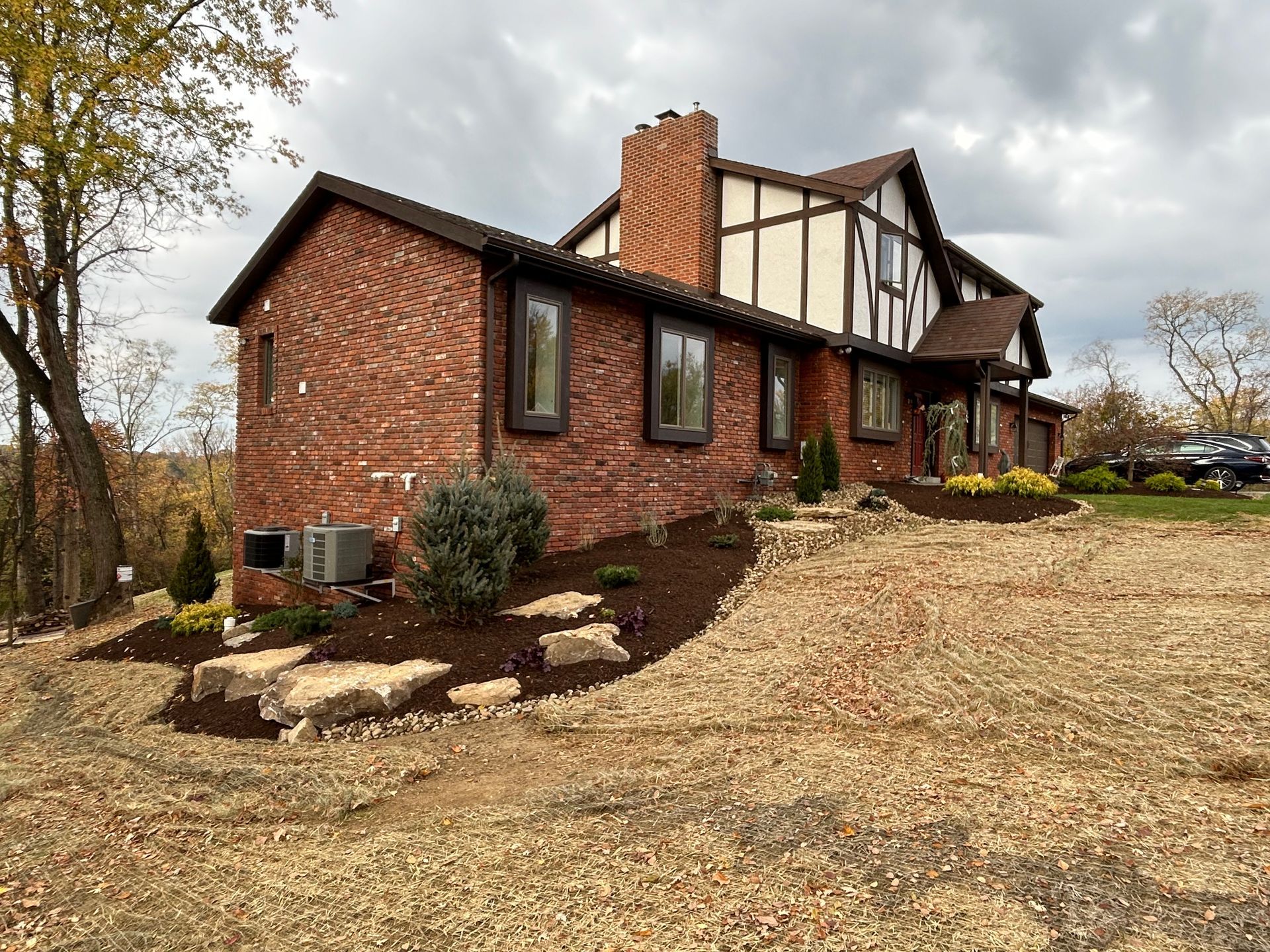 A large brick house with a lot of windows is sitting on top of a dirt hill.