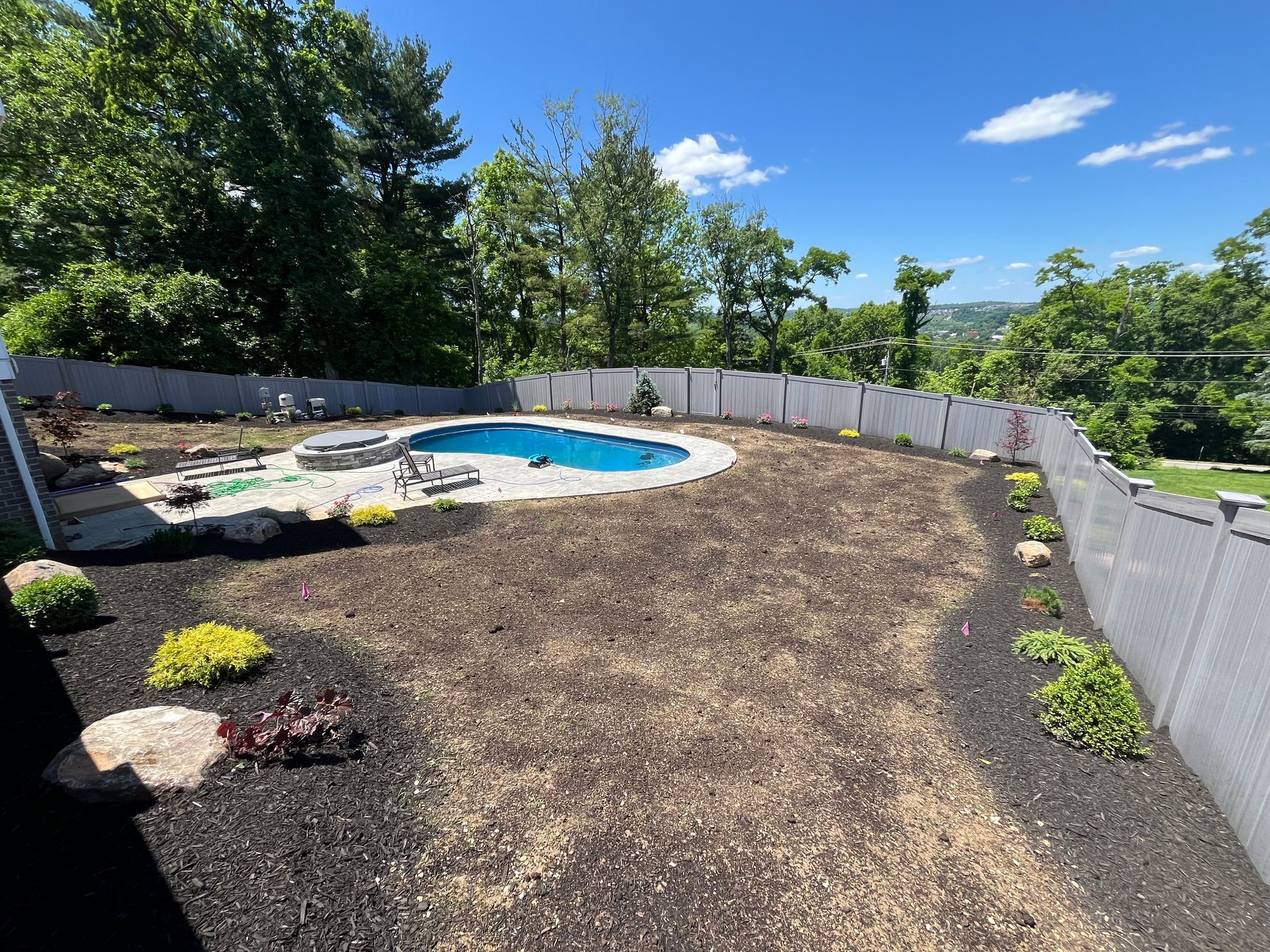 A lush green lawn with trees and mulch in front of a house.