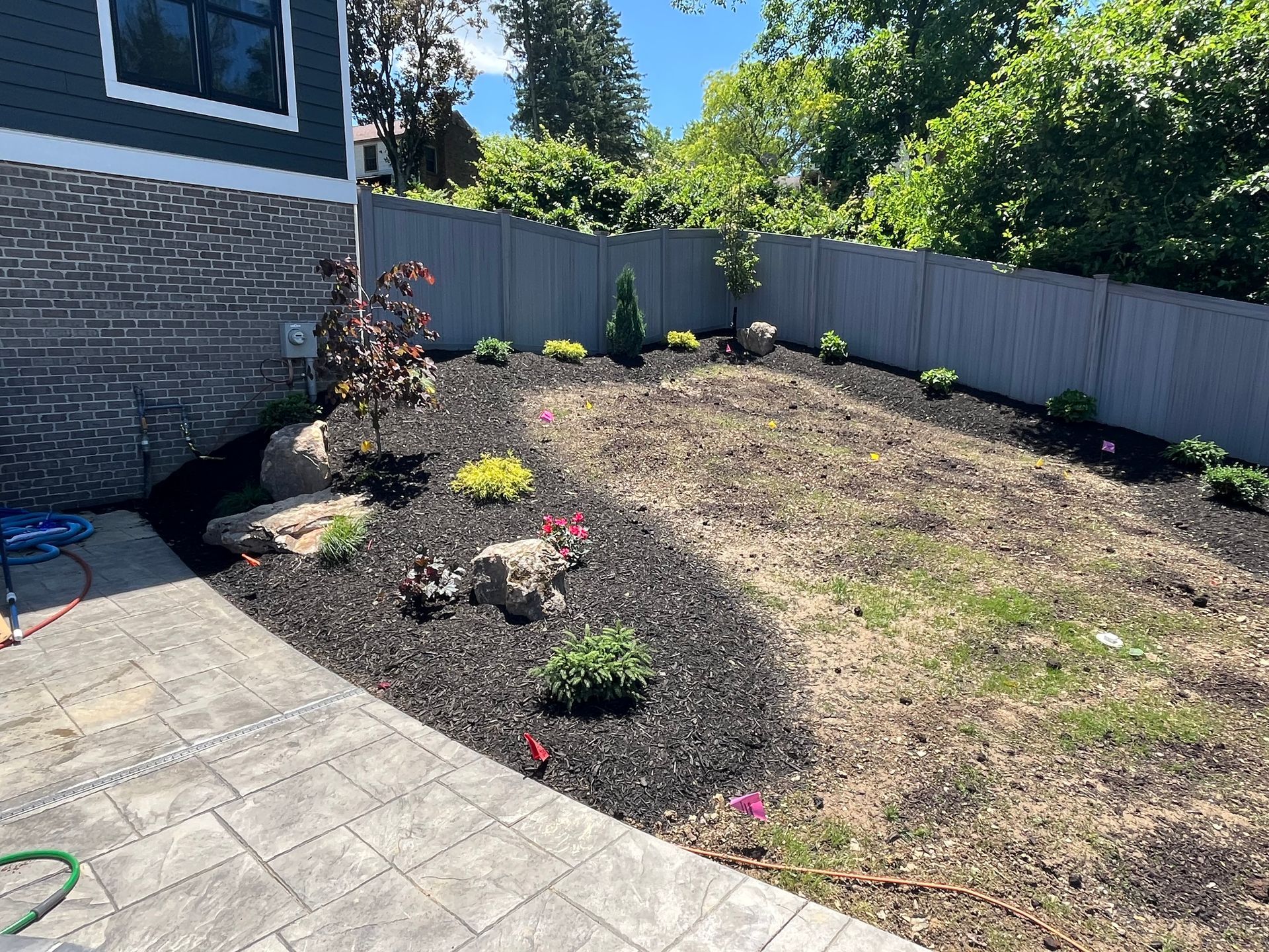 The backyard of a house with a fence and a lot of mulch.