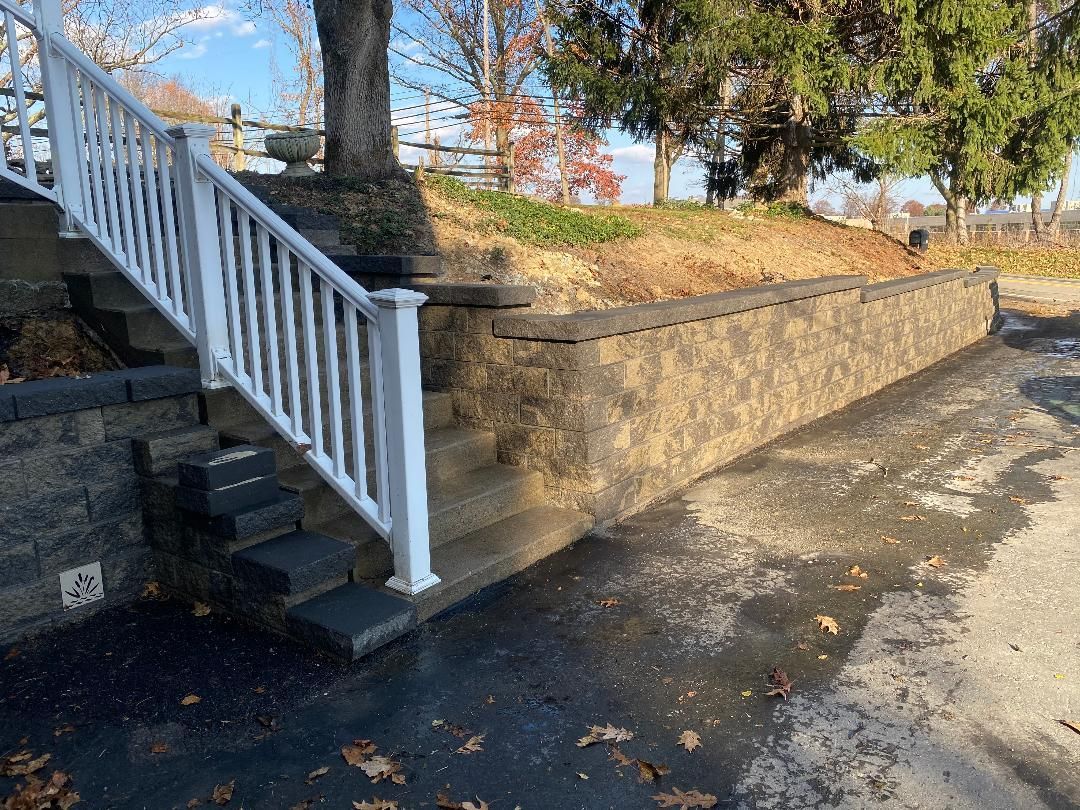 A set of stairs leading up to a stone wall with a white railing.
