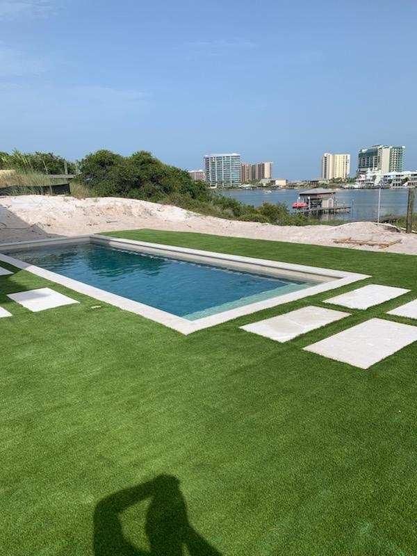 There is a large swimming pool in the middle of a lush green field.