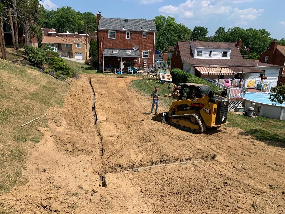 A bulldozer is working on a dirt road in front of a house.