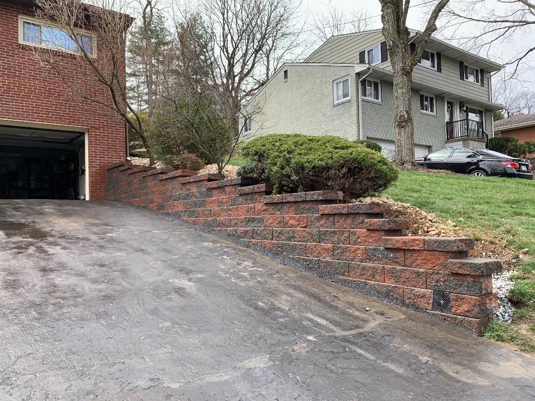 A driveway leading to a house with a brick wall and a garage.