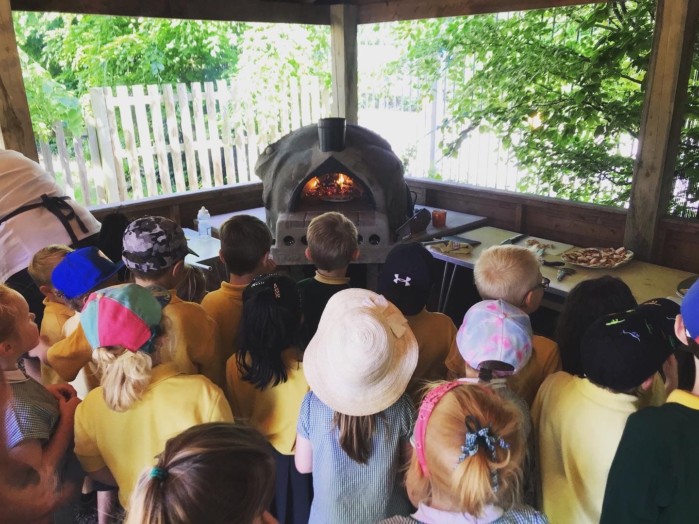 school children watching pizza baking in their school cob oven