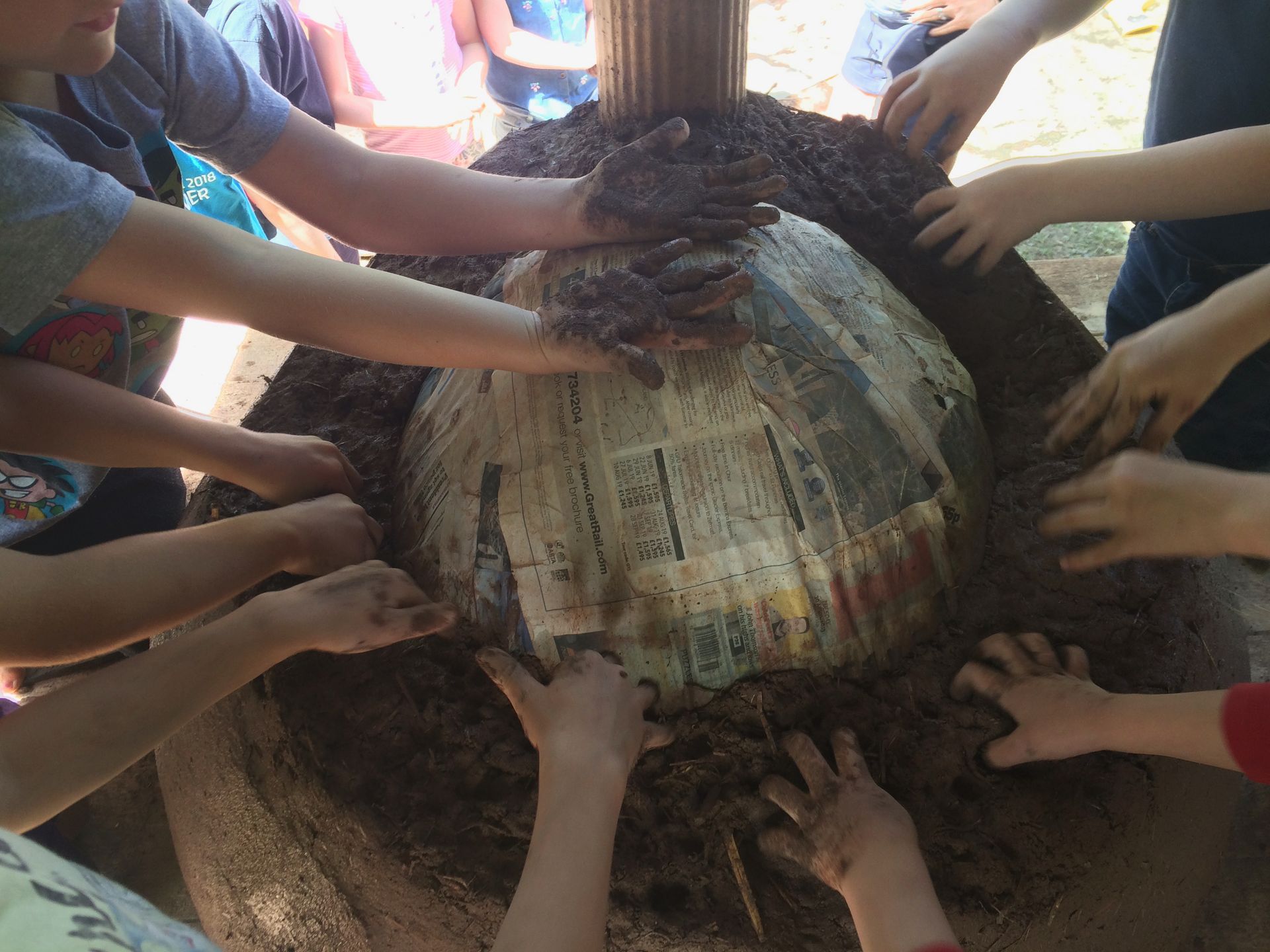 Children working together building a cob oven