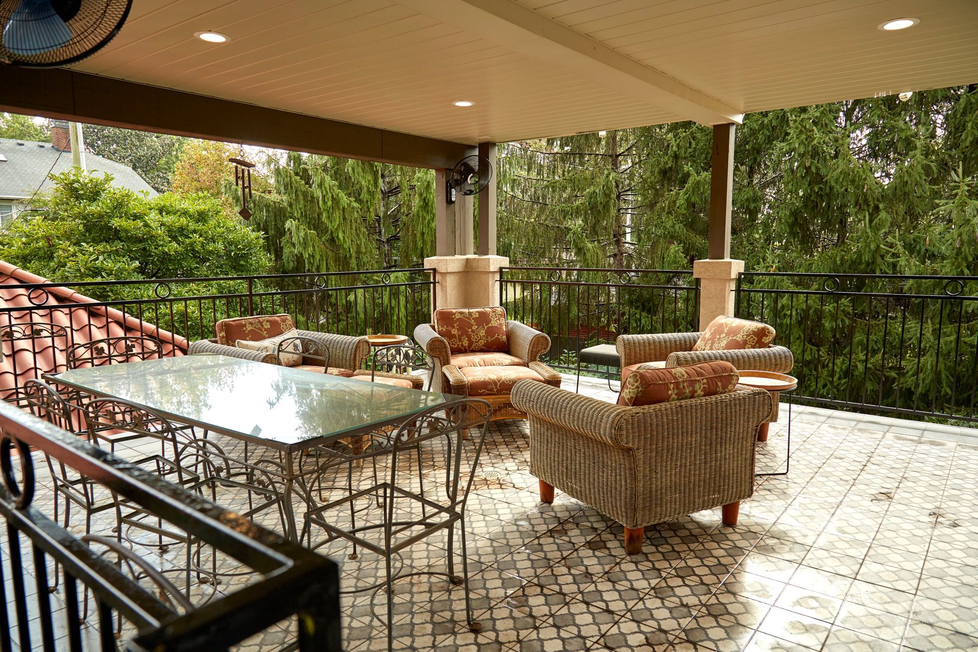A balcony with a table and chairs and trees in the background