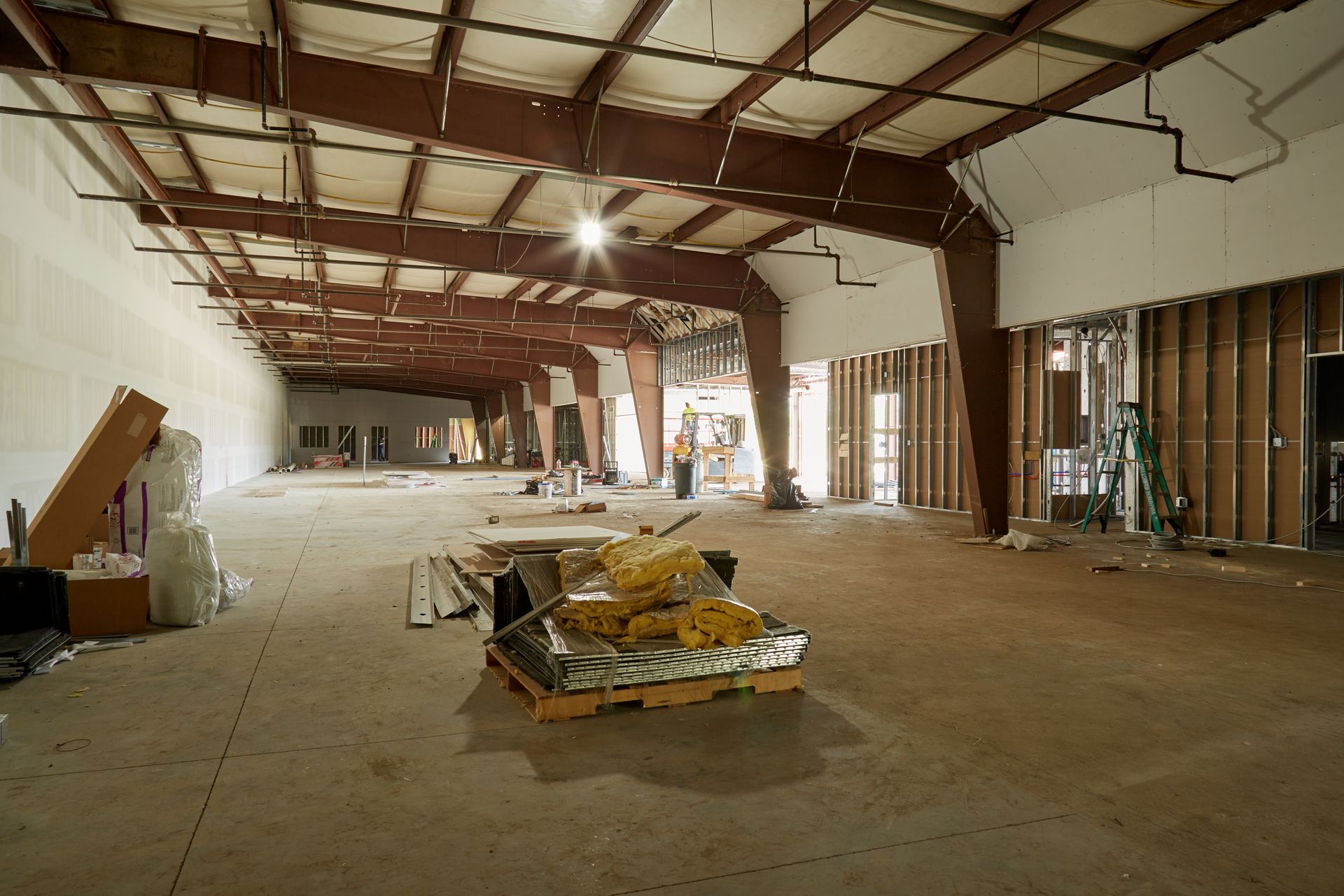 A large empty warehouse with a pallet of supplies on the floor.