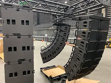 A person is holding a stack of speakers in a warehouse.
