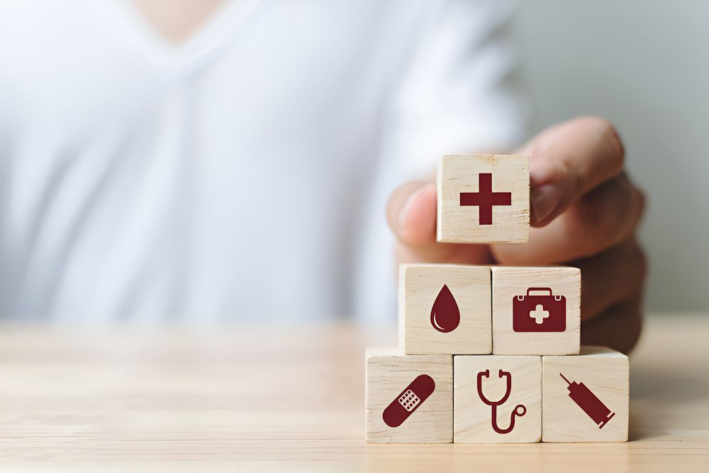 A Person Is Stacking Wooden Blocks With Medical Icons On Them — Christies Accountants & Advisors In Dubbo, NSW