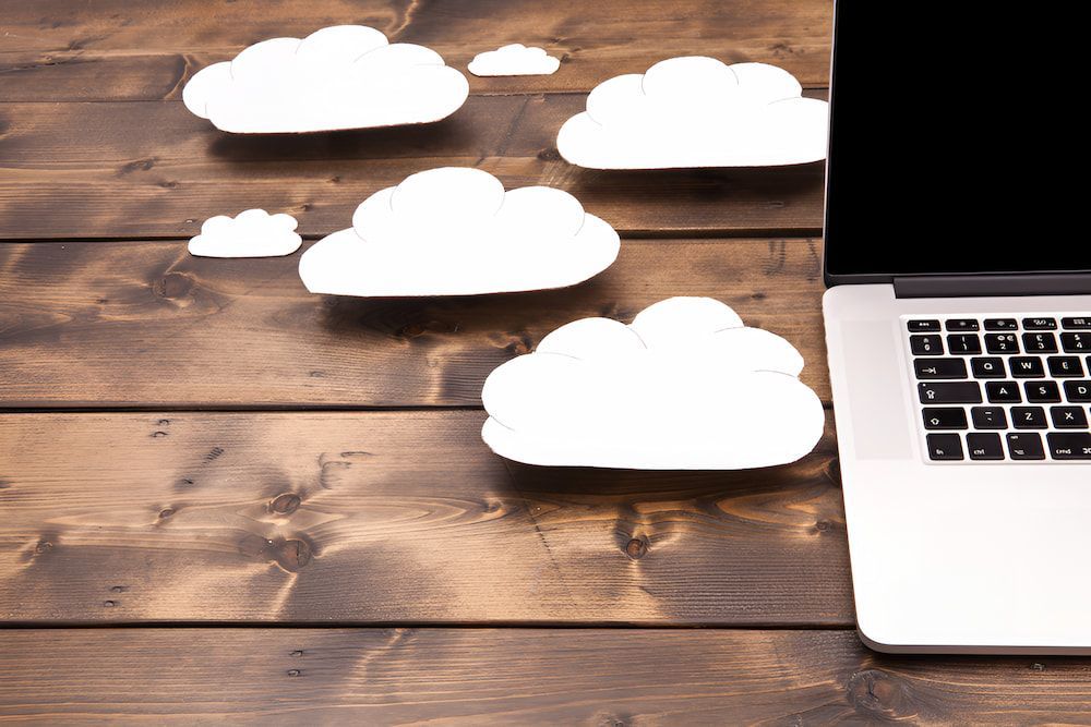 A Laptop Is Sitting On A Wooden Table Next To A Clouds — Christies Accountants & Advisors In Dubbo, NSW